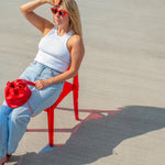 model posing on red chair with match red leather mini handbag drawstring closure
