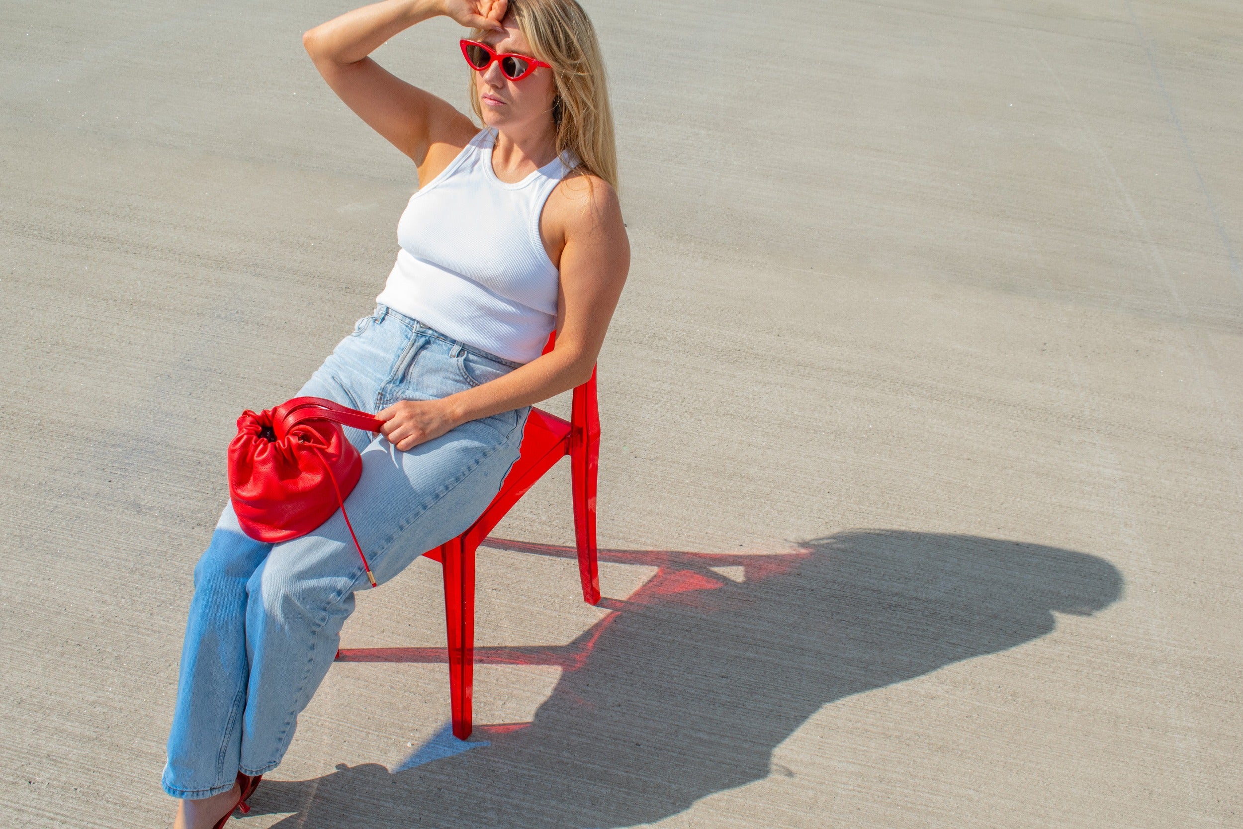 model posing on red chair with match red leather mini handbag drawstring closure
