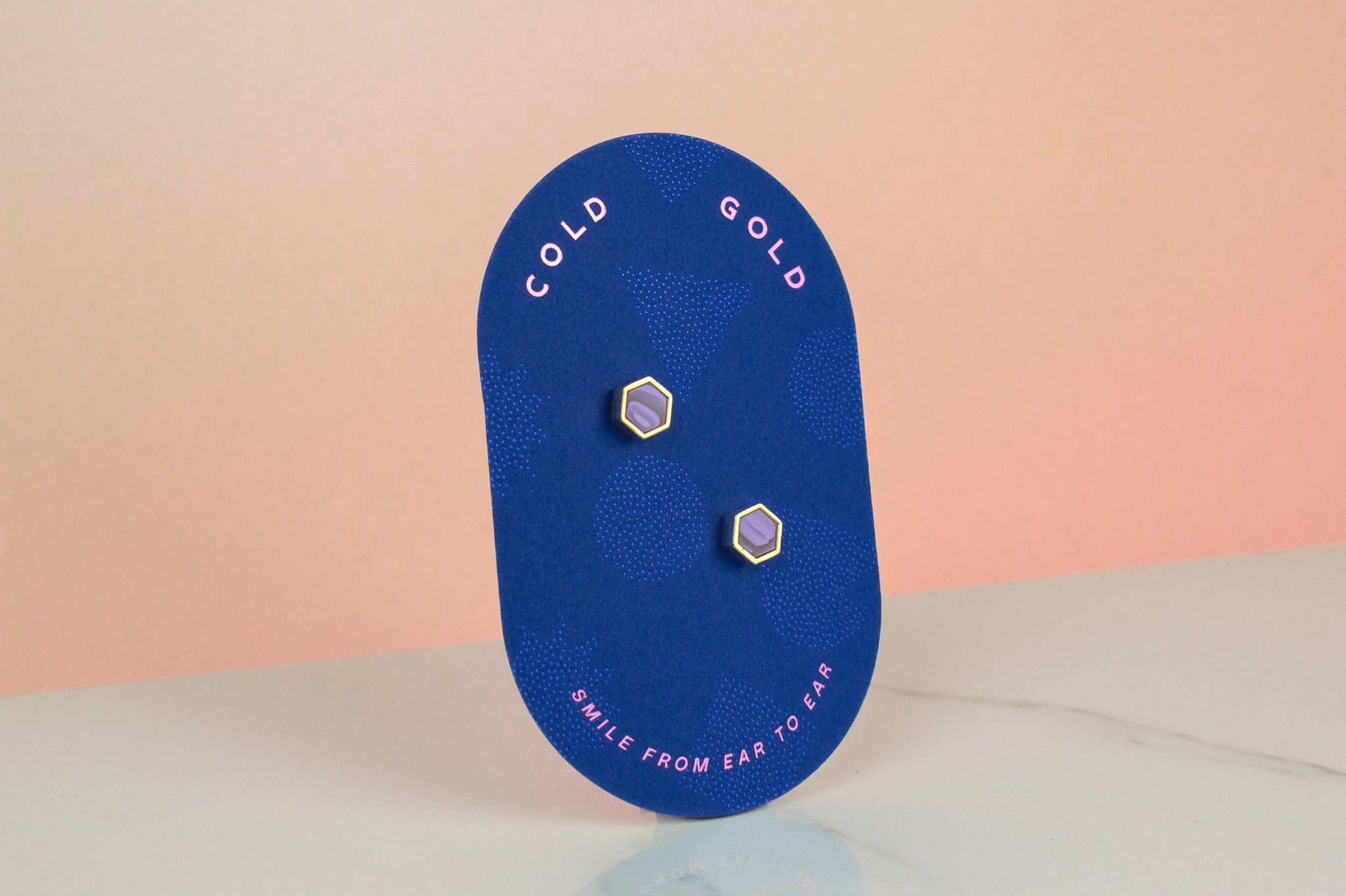 a blue backer card holding a pair of modern and minimal pastel purple hexagon earrings