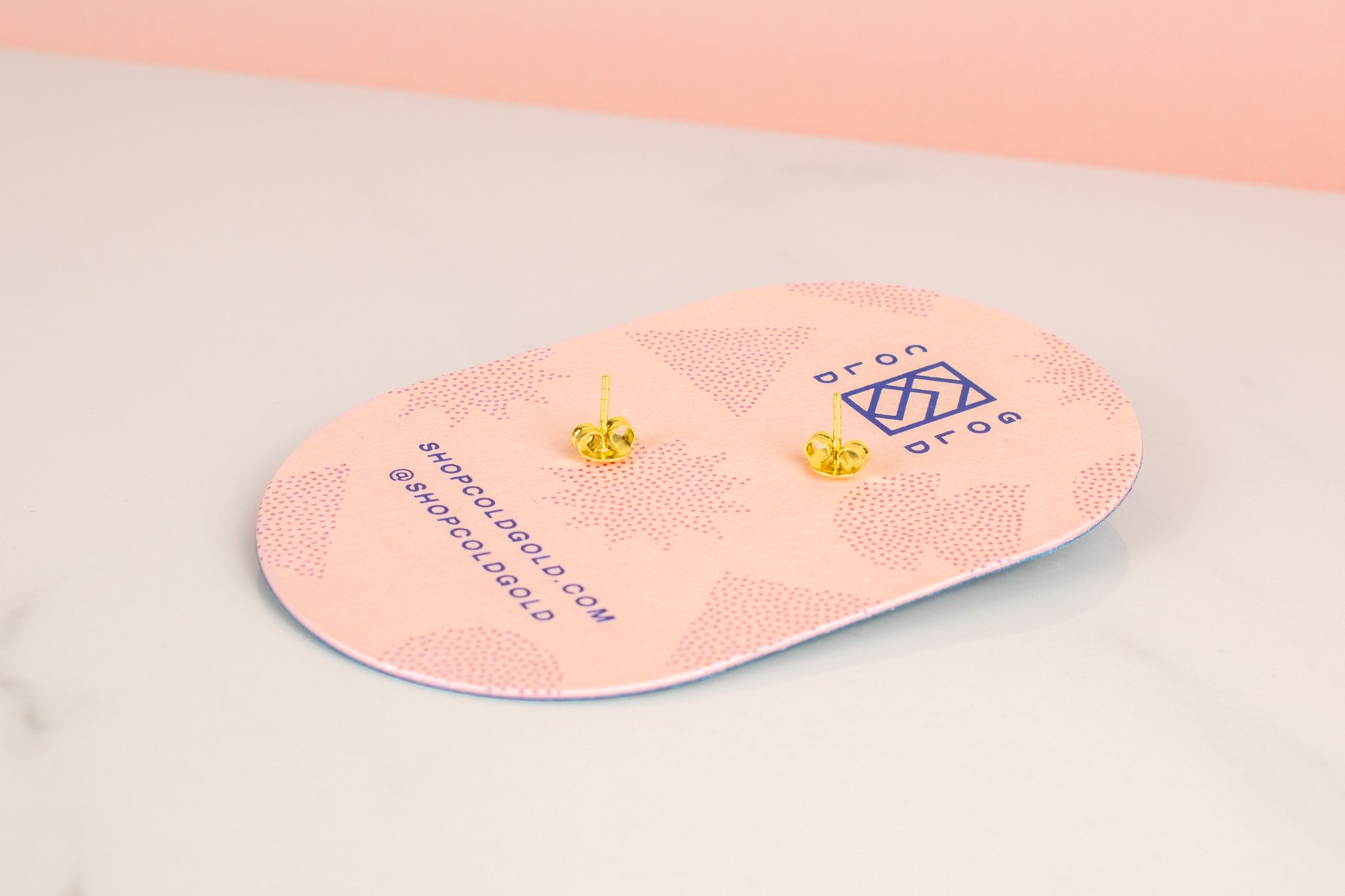 back of pink pill shaped card with cold gold logo