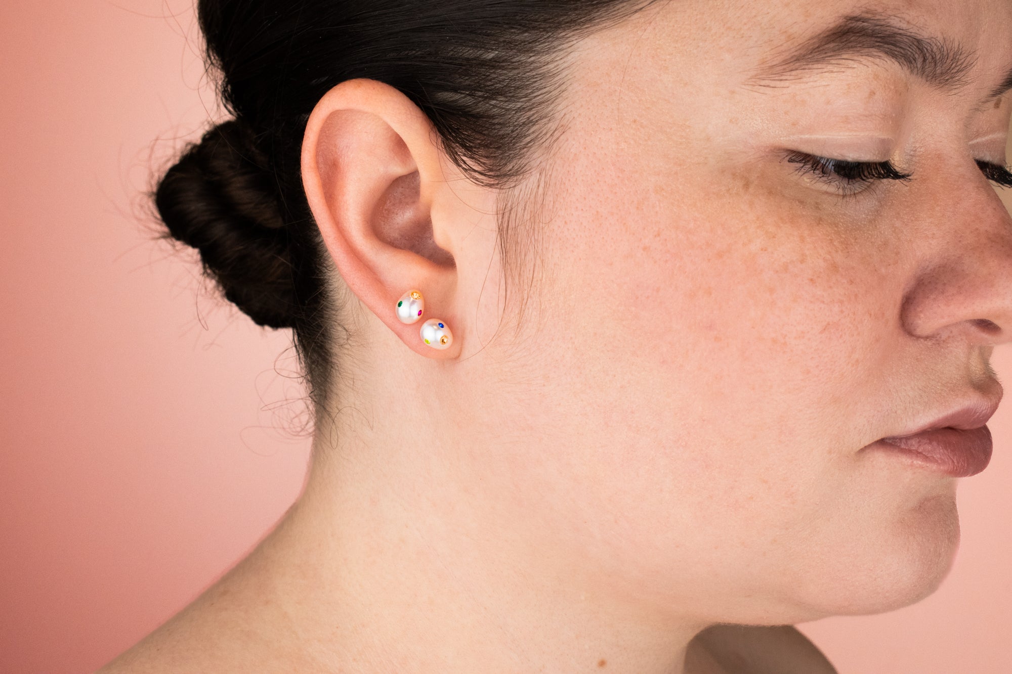 model wearing pair of baroque freshwater pearl earrings bejeweled with colorful gemstones