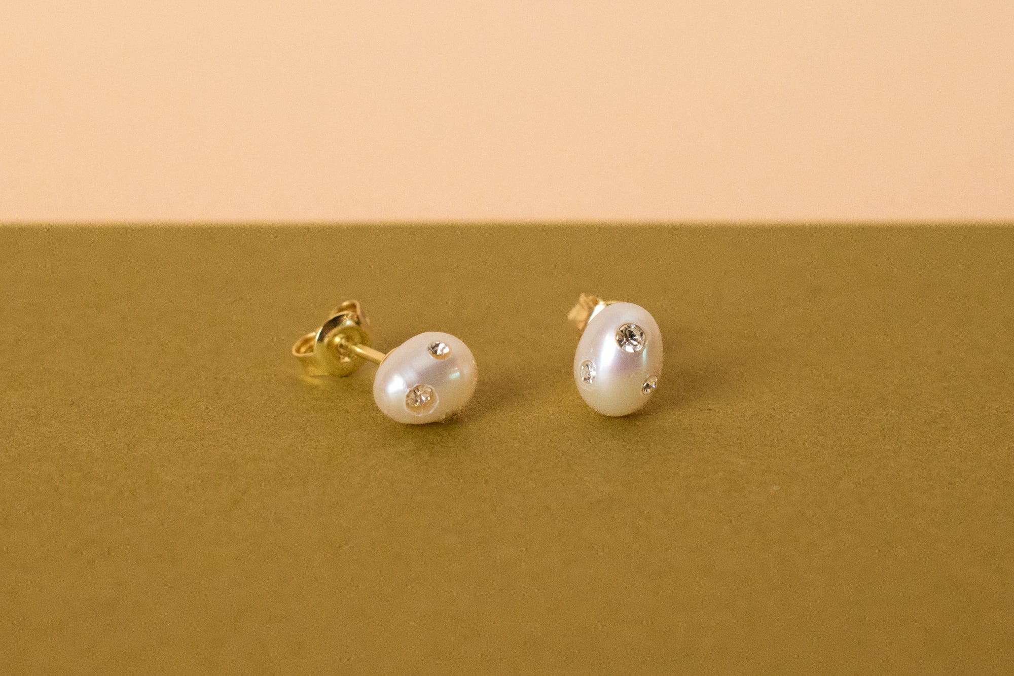 close up photo of baroque pearl stud earrings adorned with cz gemstones
