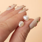 hand holding freshwater pearl earrings encrusted with gemstones