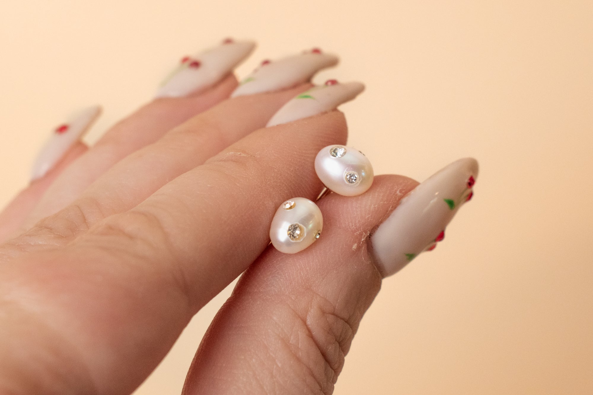 hand holding freshwater pearl earrings encrusted with gemstones