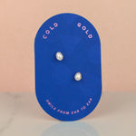 pair of bejeweled baroque pearl earrings on a cold gold branded earring card