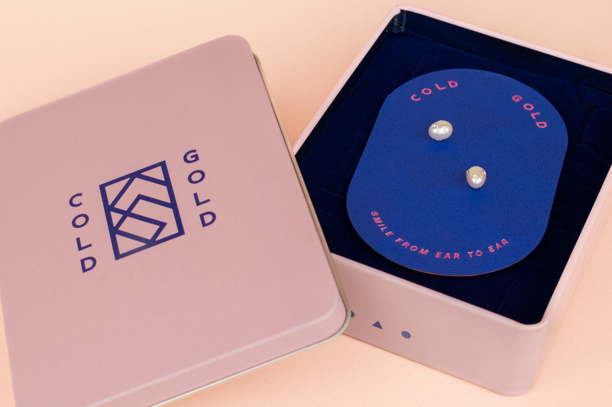 pair of freshwater pearl stud earrings with encrusted cz gemstones in cold gold branded jewelry travel tin