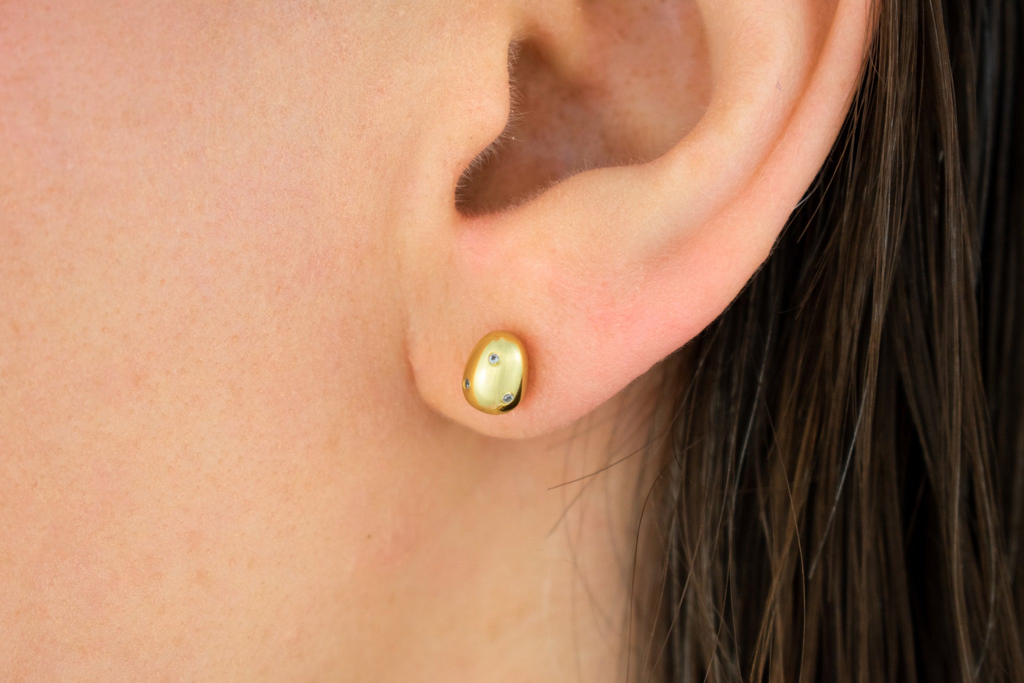 close up of model wearing 14k gold plated baroque pearl earring encrusted with tiny sparkly crystals
