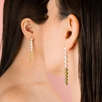 twin models facing away from camera wearing string of pearl earrings