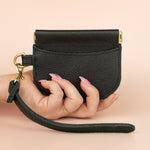 small black leather card wallet with exterior card pocket and central compartment with gold hardware and detachable matching leather keychain