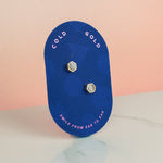 blue pill shaped card showing small quartz crystal and gold earring set gold hexagon studs gemstone earrings