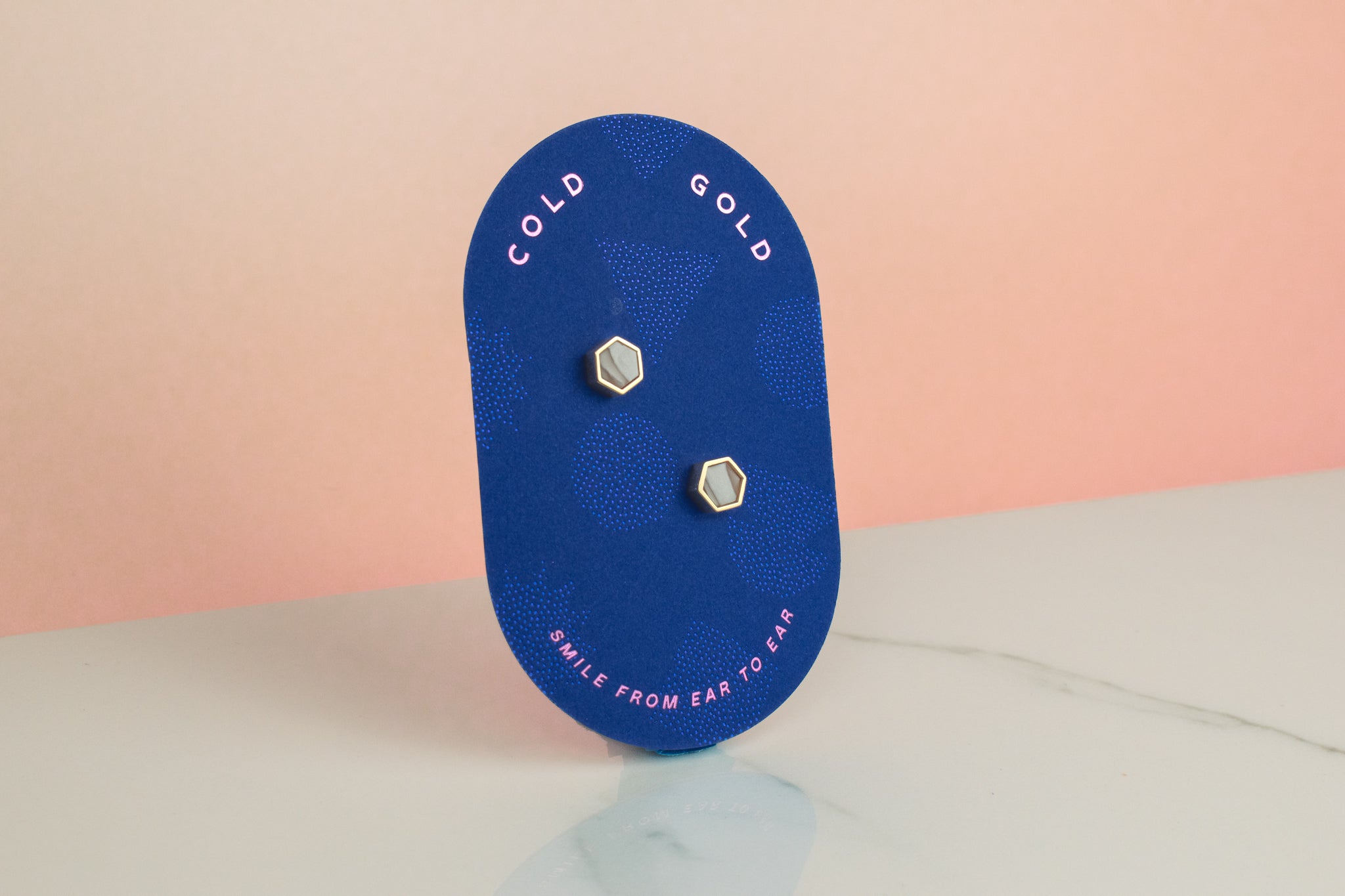 blue pill shaped card showing small quartz crystal and gold earring set gold hexagon studs gemstone earrings