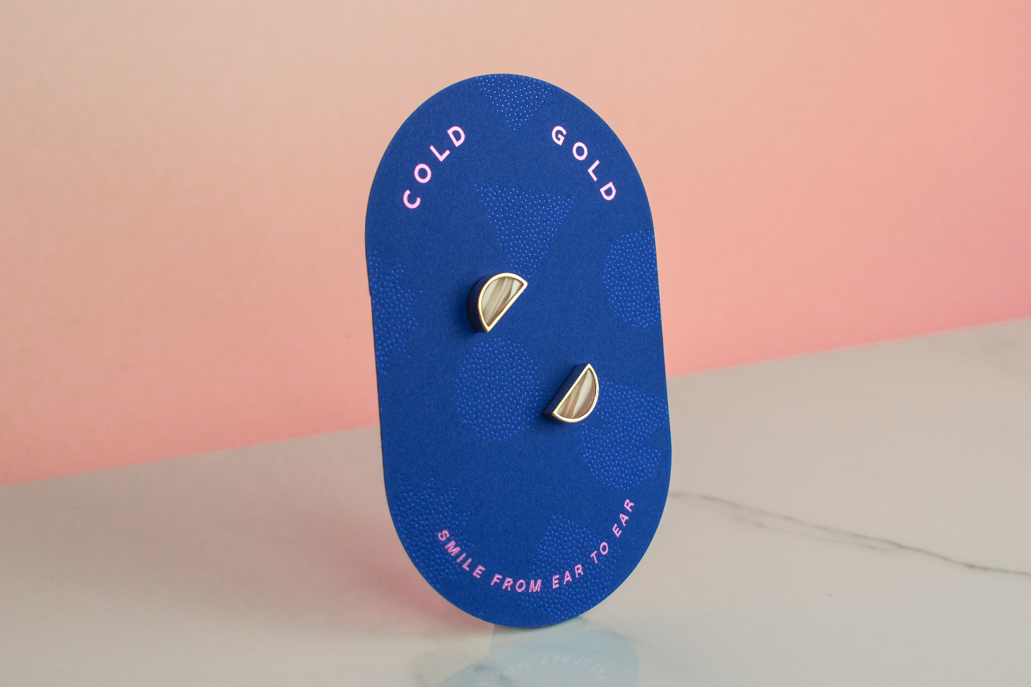 blue card displaying pair of white striped handmade crystal earrings