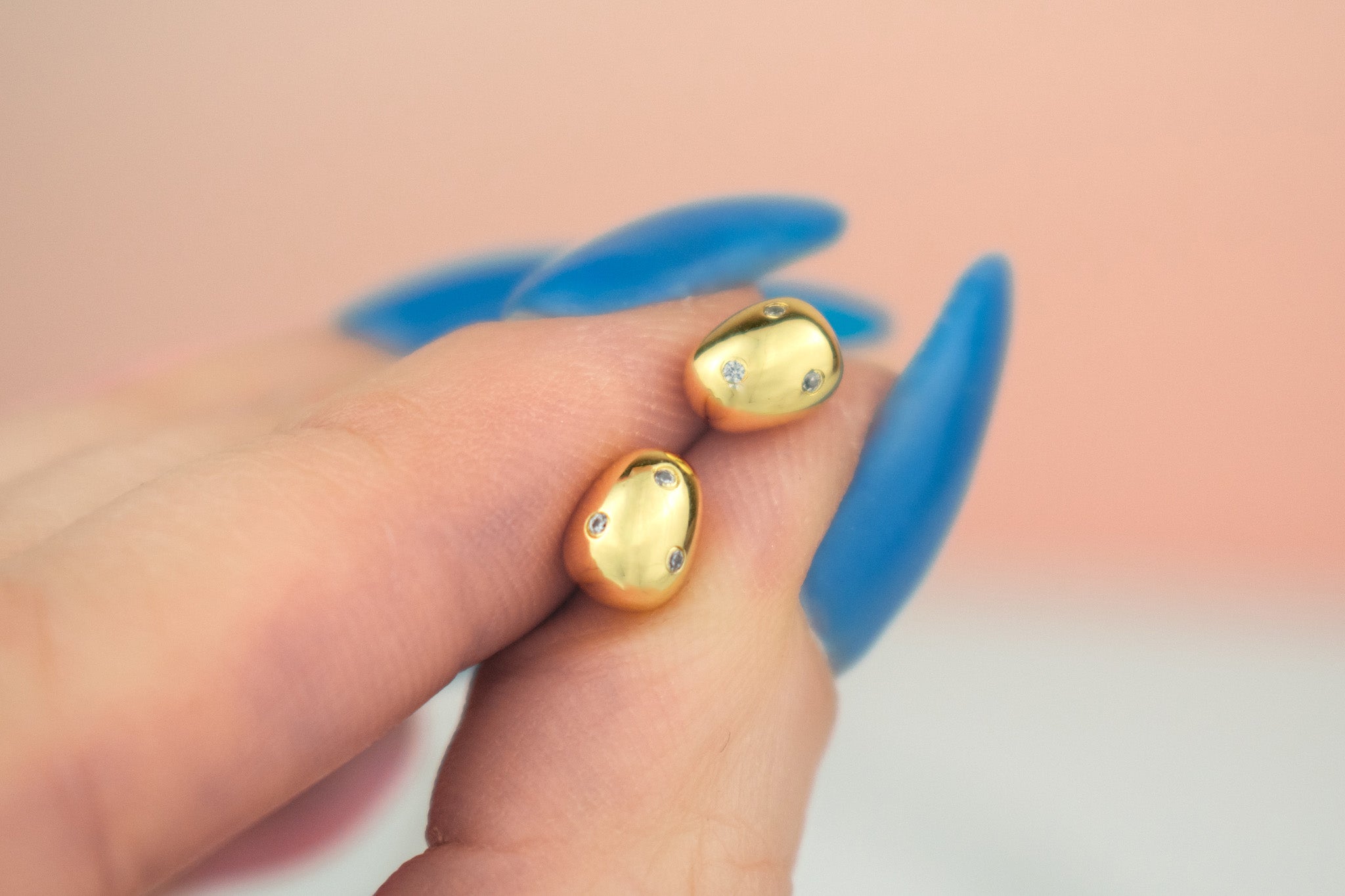 hand hold pair of gold baroque pearl earrings imbedded with micro crystal gemstones