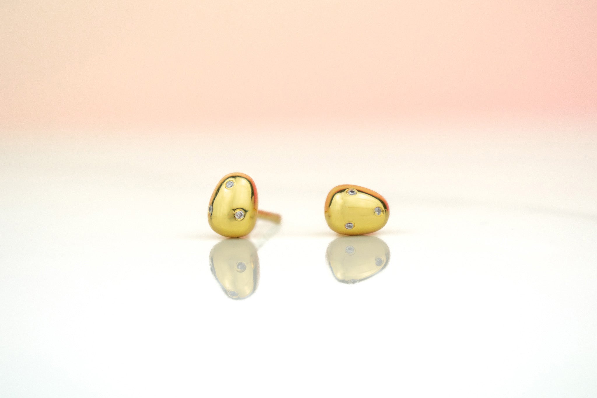 close up of 14k gold plated pearl studs encrusted with crystal gemstones