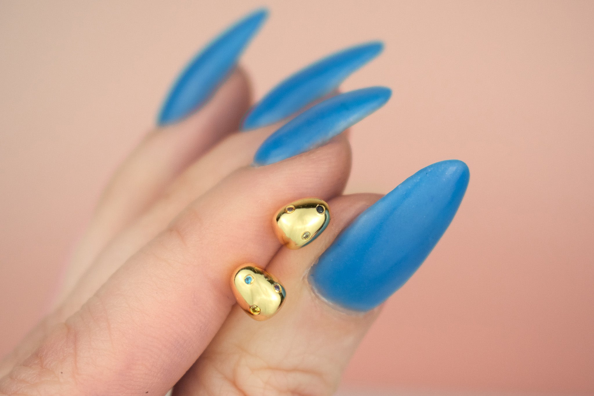 close up of 14k gold plated pearl earrings encrusted with aquamarine, chartreuse, marigold, black gemstones