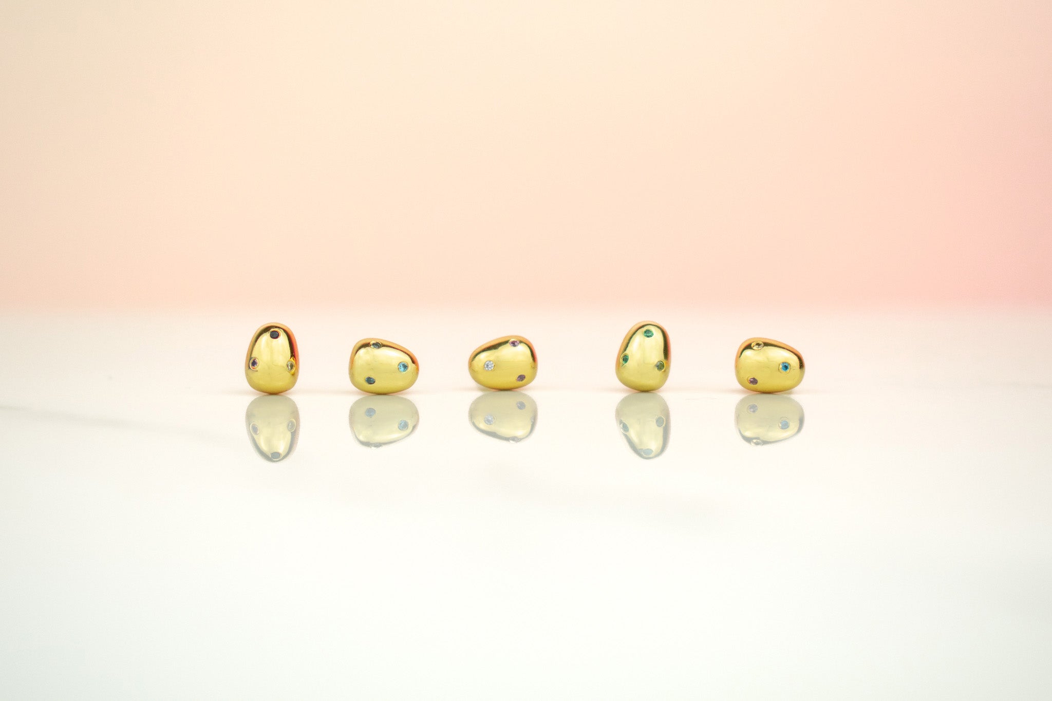 row of 14k gold plated baroque pearl earrings incrusted with tiny multicolored rainbow gemstones with sterling silver posts