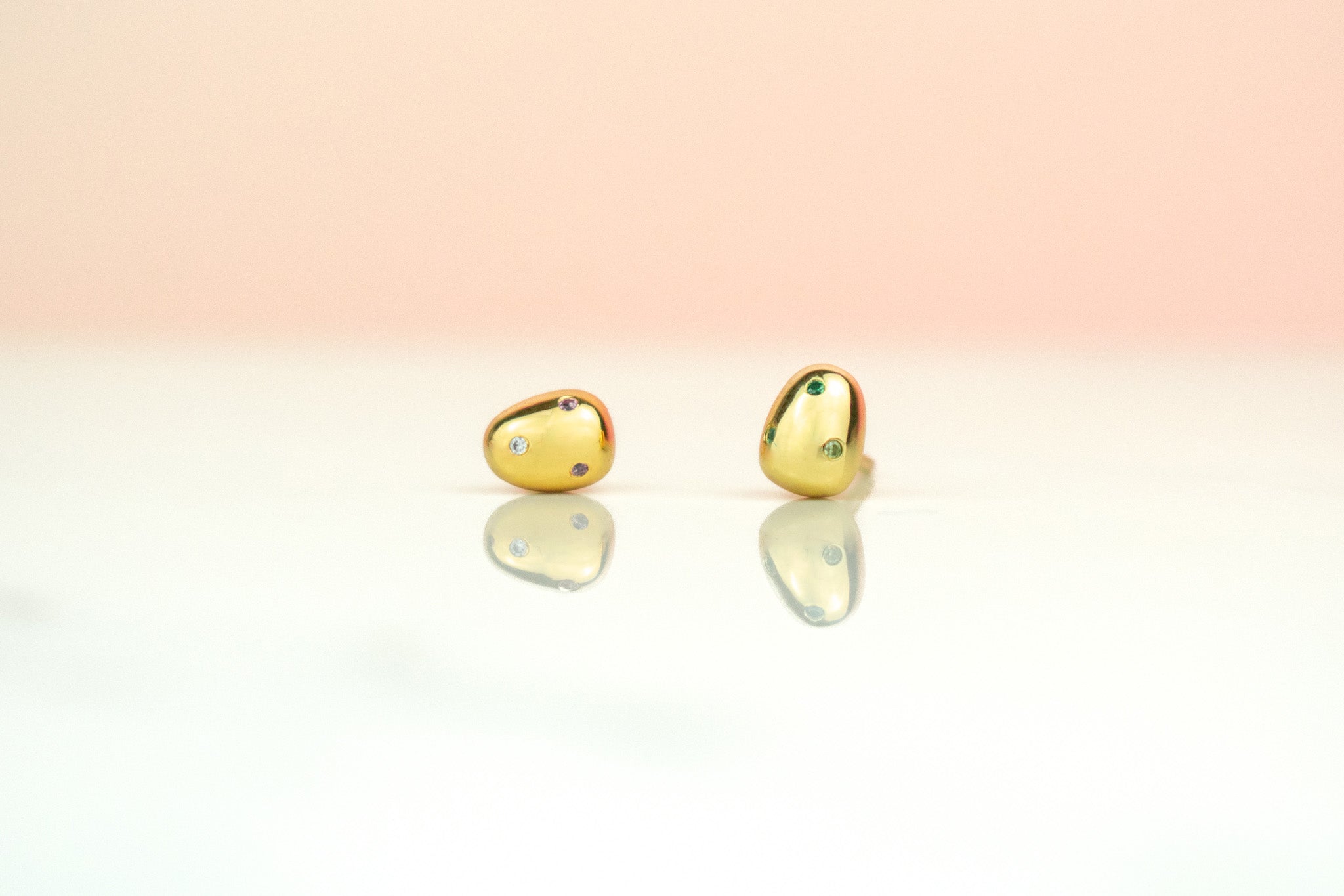 close up of baroque pearl earrings encrusted with micro gemstones in various colors