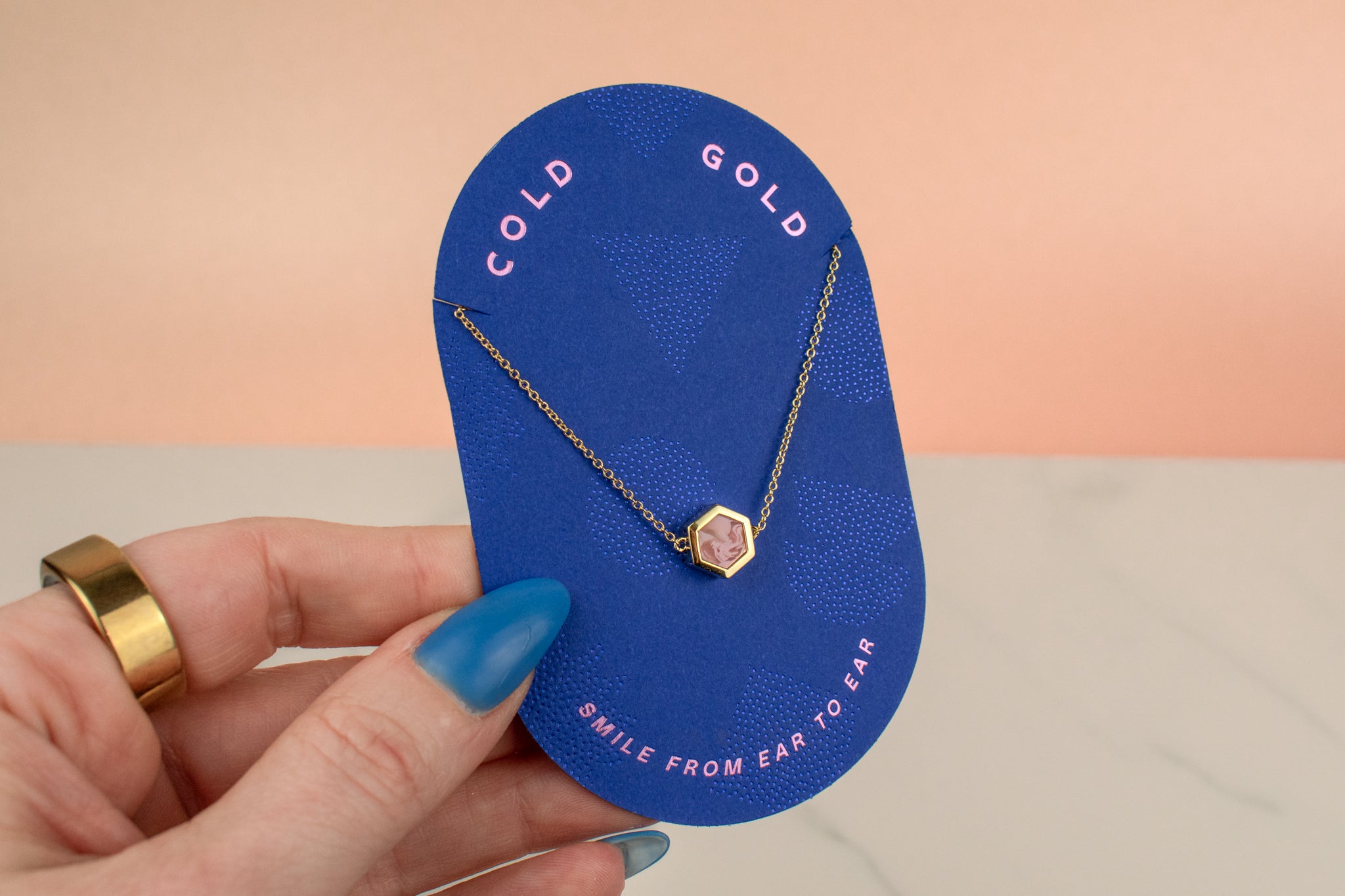 hand holding blue card displaying light pink polymer clay hexagon delicate necklace