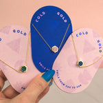 pink pill shaped cold gold cards displaying three 14k gold geo chain gemstone inspired necklaces in emerald, sapphire, and rose quartz