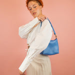 model putting on bright blue genuine pebbled leather shoulder bag