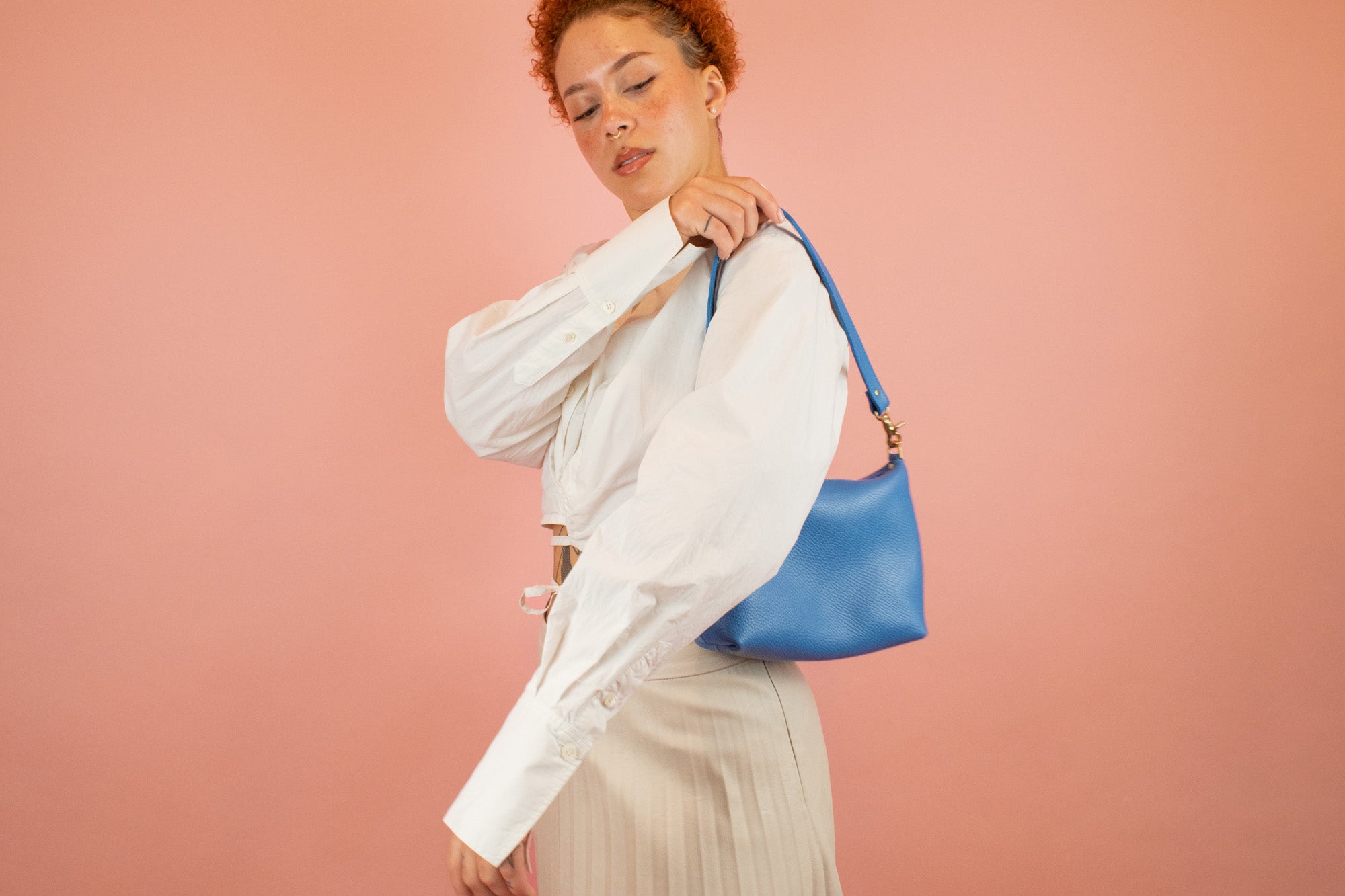 model putting on bright blue genuine pebbled leather shoulder bag