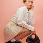 model kneeling down posing with slouchy handbag with convertible design in black leather