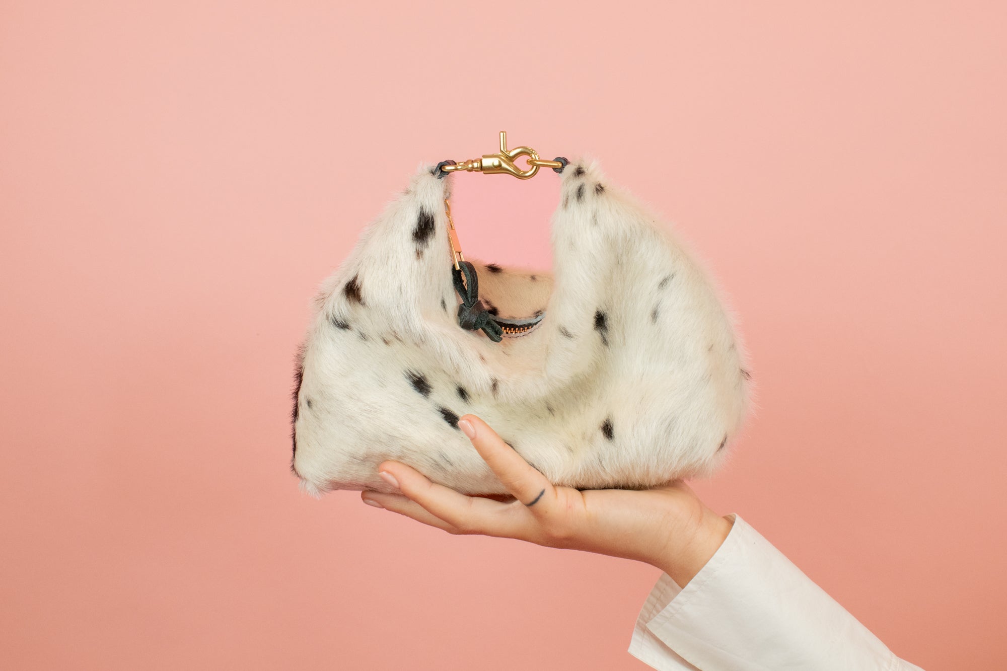 mini crescent slouchy handbag with convertible design in leather cowprint sitting on models outstretched hand