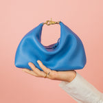 bright blue slouchy mini leather handbag with relaxed silhouette sitting a top models hand
