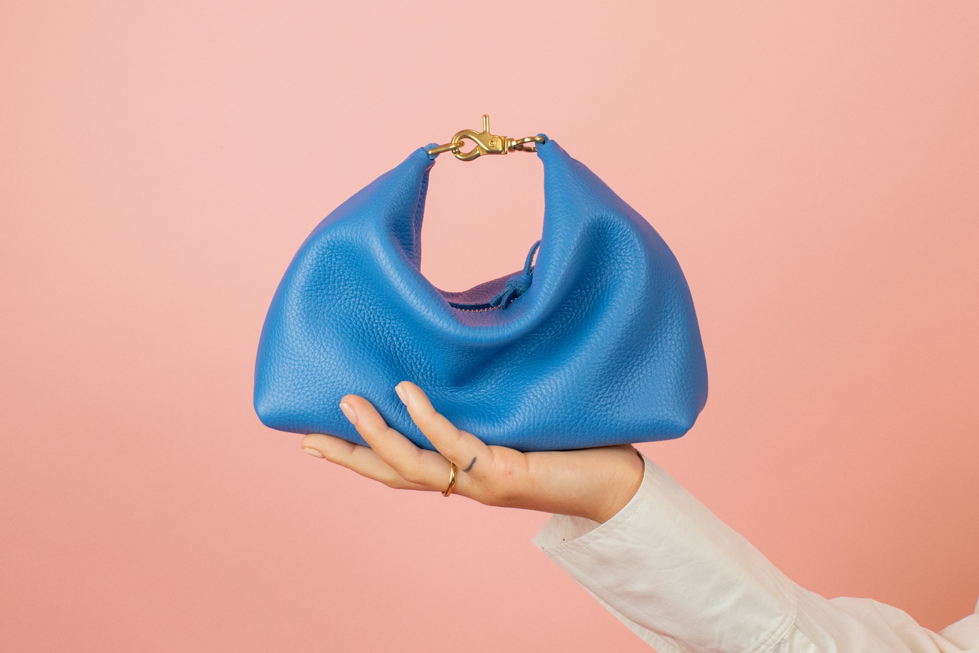 bright blue slouchy mini leather handbag with relaxed silhouette sitting a top models hand