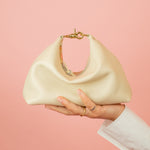 cream slouchy leather crescent handbag sitting a top models hand