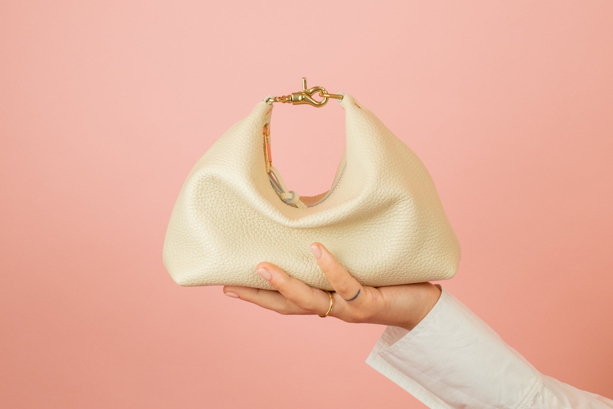 cream slouchy leather crescent handbag sitting a top models hand