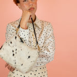 model holding up leather hair-on-hide handbag in cowprint