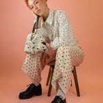 model wearing matching polka dot suit with gold lariat while holding up speckled hair-on-hide mini leather wristlet