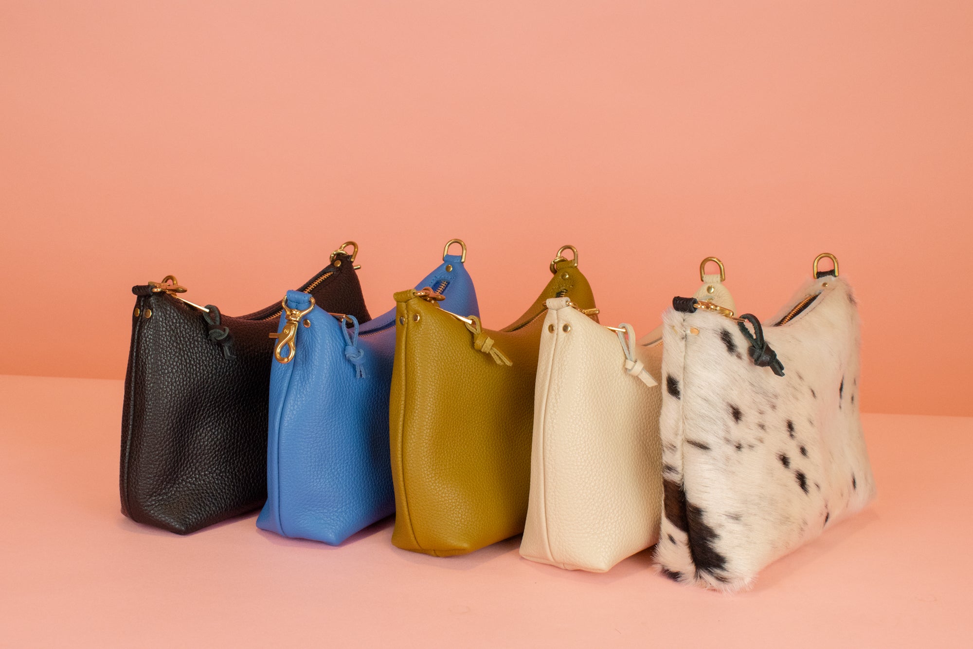 chic leather shoulder bags line up in a row in black, matisse blue, olive green, bone white, cowprint