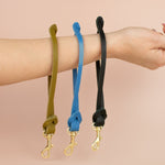 avocado green keychain, bright blue wristlet, and modern black leather wristlet keychain dangling from wrist