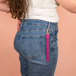 model wearing hot pink nubuck keychain with brass hardware clipped onto denim belt loop