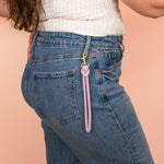 model wearing lilac genuine pebbled leather keychain with brass hardware hooked to belt loop