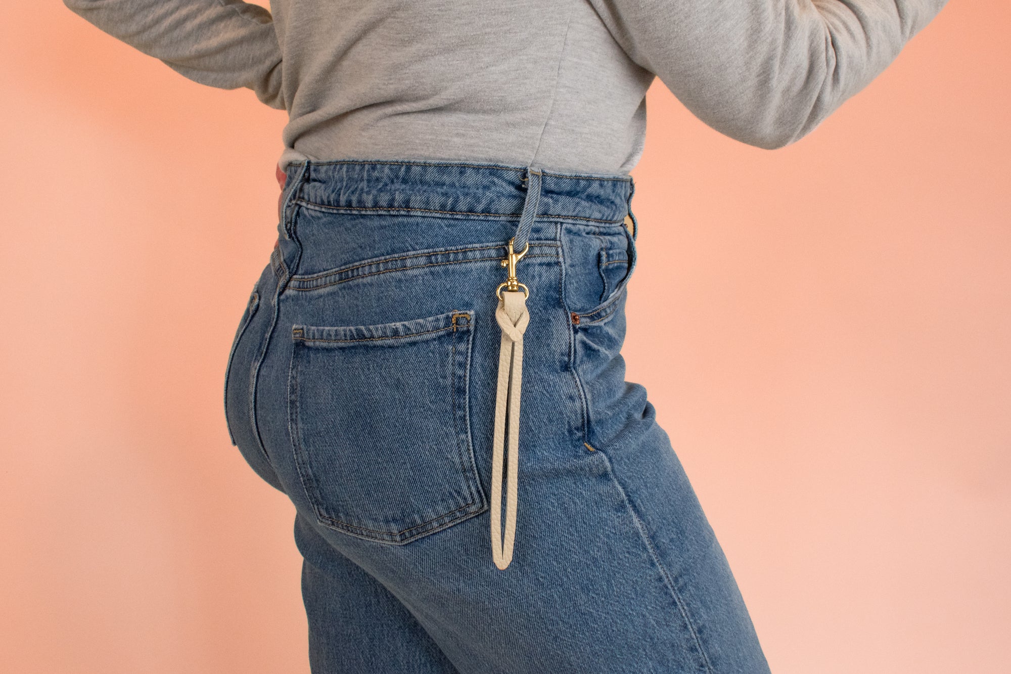 model wears handmade knotted leather keychain clipped onto blue jeans belt loop