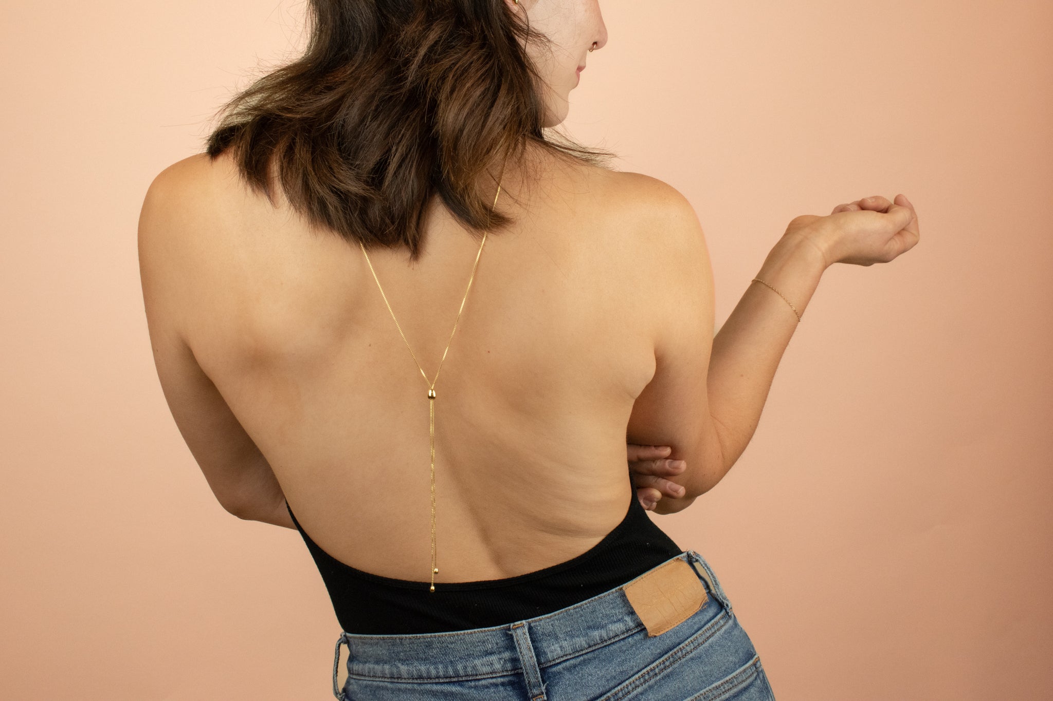 model in backless bodysuit styling lariat y chain necklace backwards