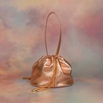 metallic pink slouchy leather handbag with ruched drawstring closure