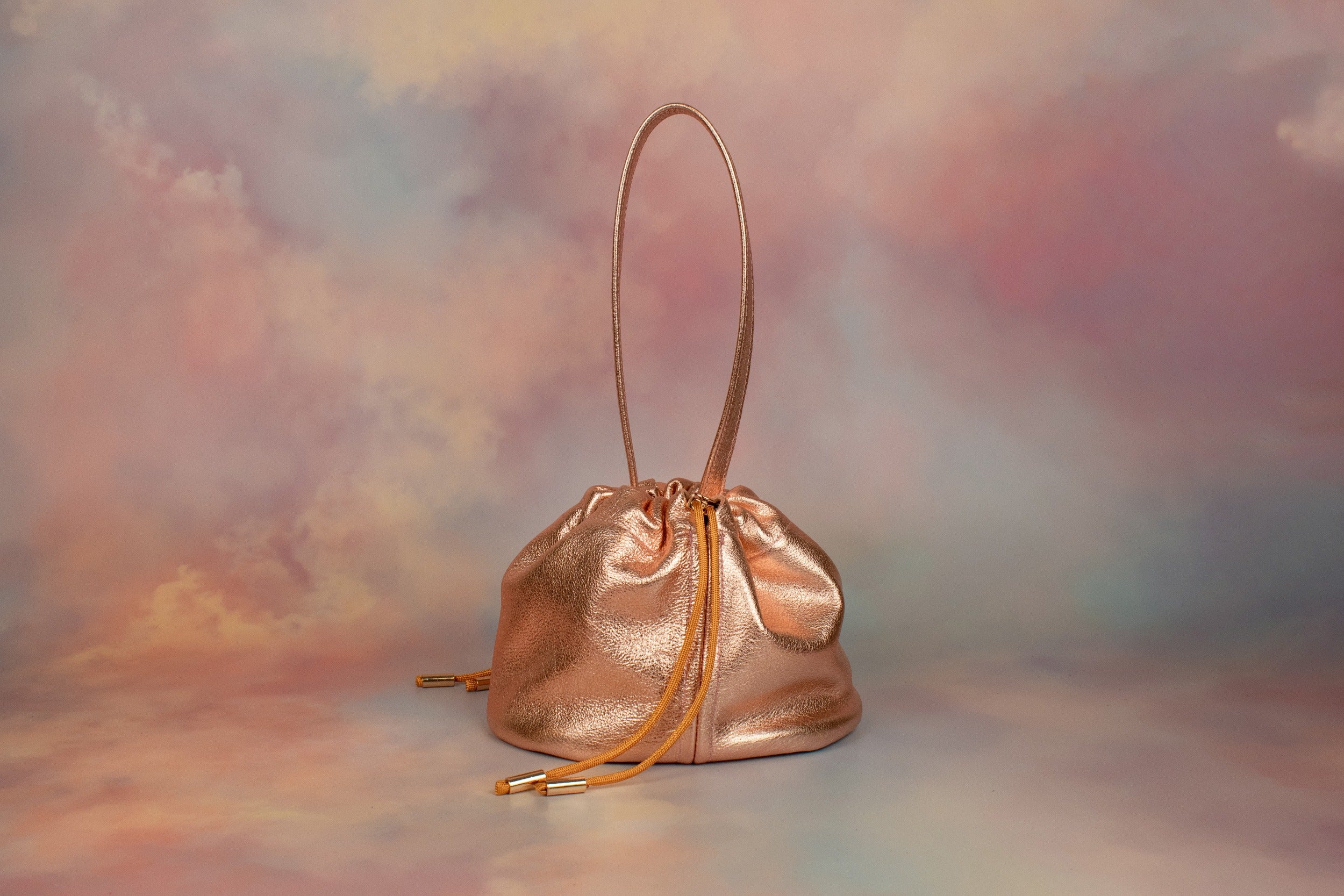 metallic pink slouchy leather handbag with ruched drawstring closure