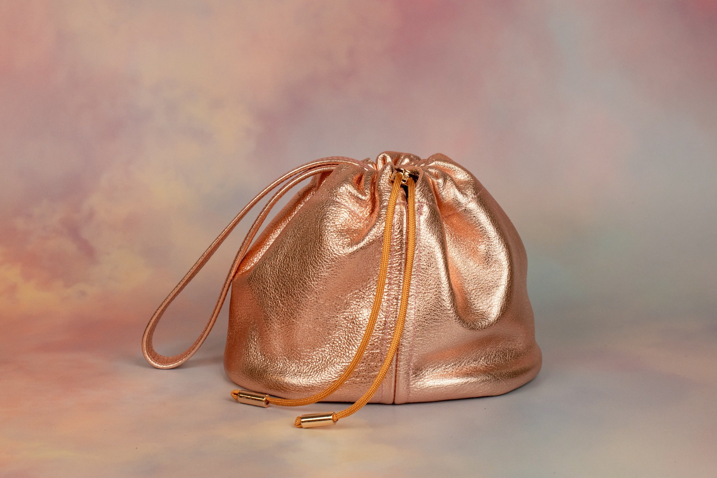 metallic rose gold leather ruched drawstring handbag with gold hardware