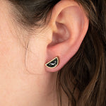 close up shot of model wearing semi circle geometric earrings handmade with matte black clay and tiny chips of white clay