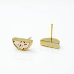 close up of gold and white minimalist geometric studs in terrazzo style on marble reflective background