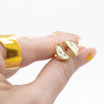 manicured hand holding pair of white stone stud earring set plated in gold