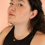 model wearing matching gold geometric earrings and necklace in white terrazzo style