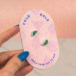 a hand holding pink card with a pair of blue green crystal quartz triangle geo stud earring set on it