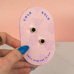 hand holding a pink backer card displaying pair of matte black handmade polymer clay gold hexagon stud earrings