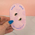 hand holding a set of three geometric earrings on geometric packaging showing 14k gold jewelry, half moon studs in black obsidian