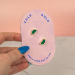 pink geometric card showing a pair of emerald studs with 14k gold plated moon stud earrings on a white background, great for September birthstone gift